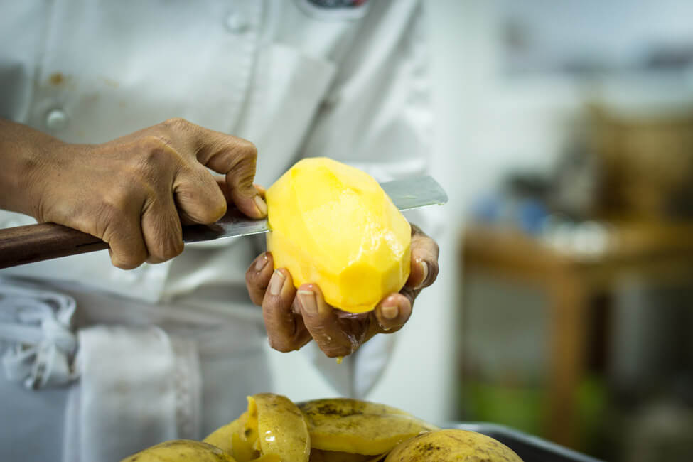 Thailänderin schneidet gelbe Thai Mango