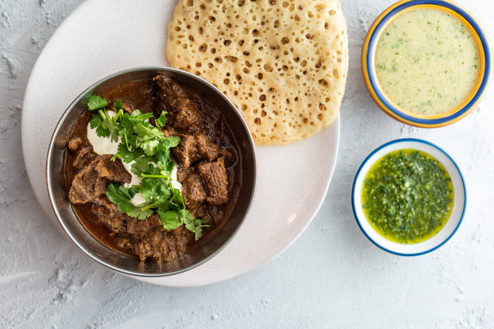 Jemenitischer Rindfleisch-Eintopf mit Sauerrahm und Koriander, serviert in Schale, dazu Lachuch und zwei Dips: Hilbeh und Zhug, aus Kitchen Impossible.