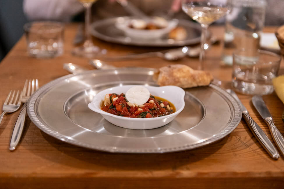 Tomatensugo mit Basilikum, Pinienkernen und Mozzarella serviert in weißem Porzellanschälchen