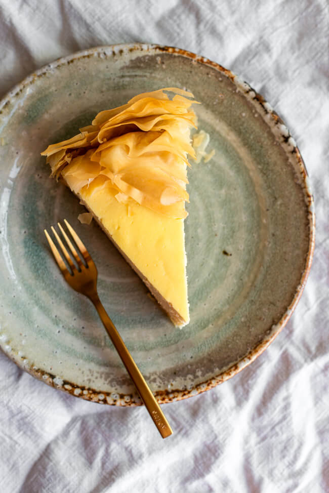 Ein Stück Baklava Käsekuchen auf Keramikteller mit goldener Gabel