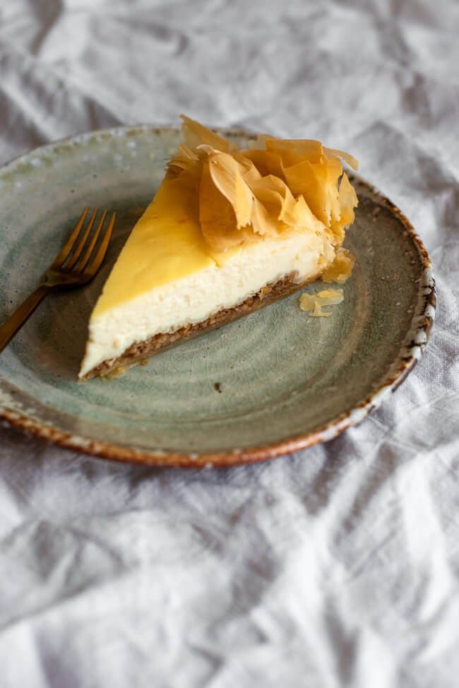 Ein Stück Baklava Käsekuchen auf Keramikteller mit goldener Gabel