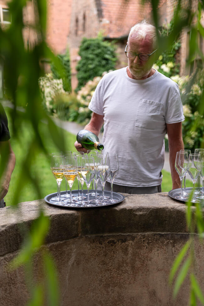 Rudolf Rudi May schenkt Frankensekt Silvaner Brut Nature im Klostergarten des Germanischen Nationalmuseum Nürnberg in Gläser ein