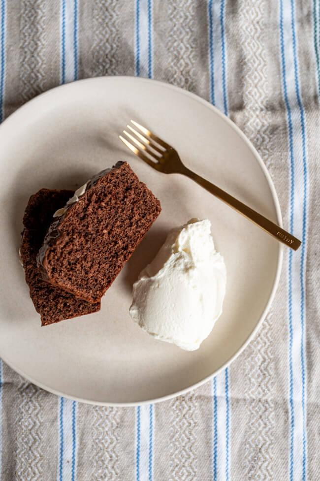 Zwei Stücke Isländischer Zimtkuchen mit Skyr auf hellem Teller mit goldener Gabel und gemusterter Tischdecke.