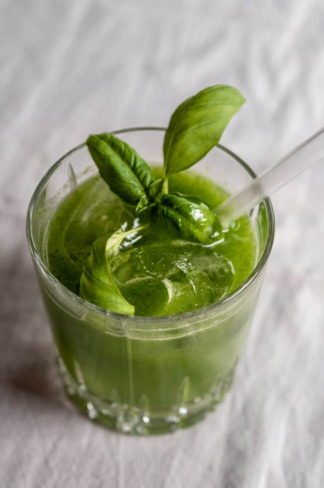 Gin Basil Smash angerichtet in Tumbler mit Eis und Baislikumblatt
