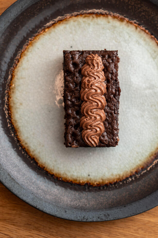 Ein Stück Gewürzkuchen mit Schokoladenbuttercreme auf Keramikteller