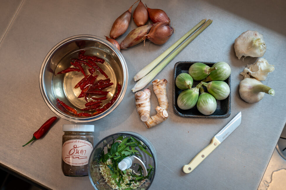 Zutaten für eine thailändische rote Currypaste auf Edelstahlarbeitsplatte ausgelegt